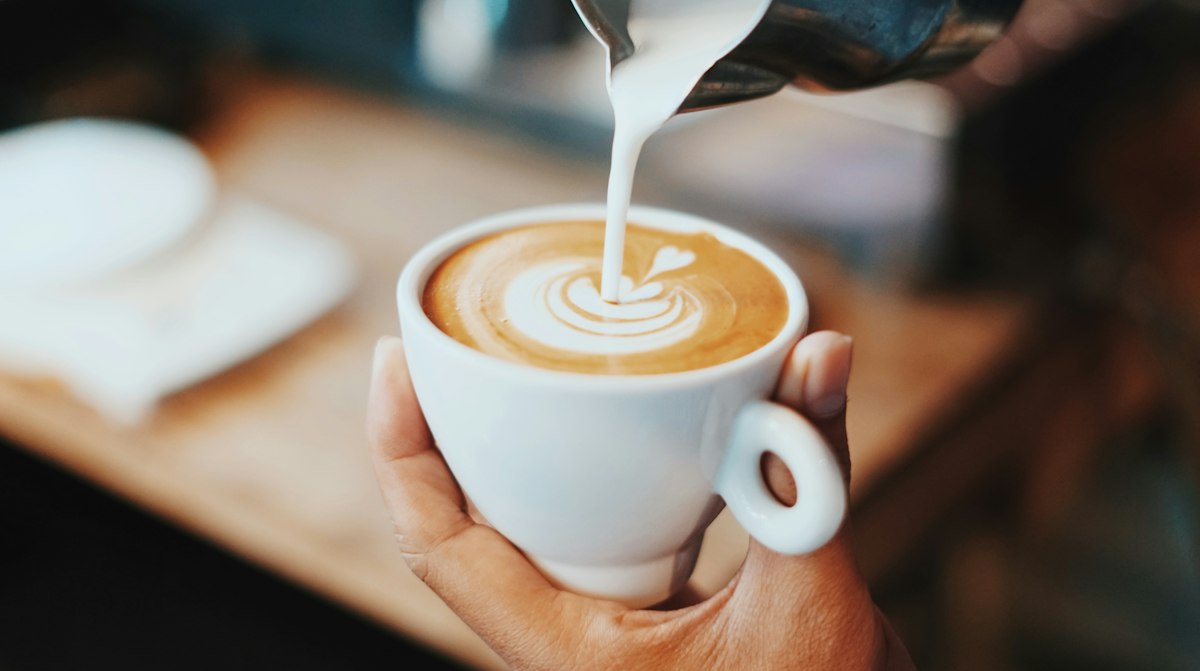 Barista pouring steamed milk into coffee in Malang, Indonesia